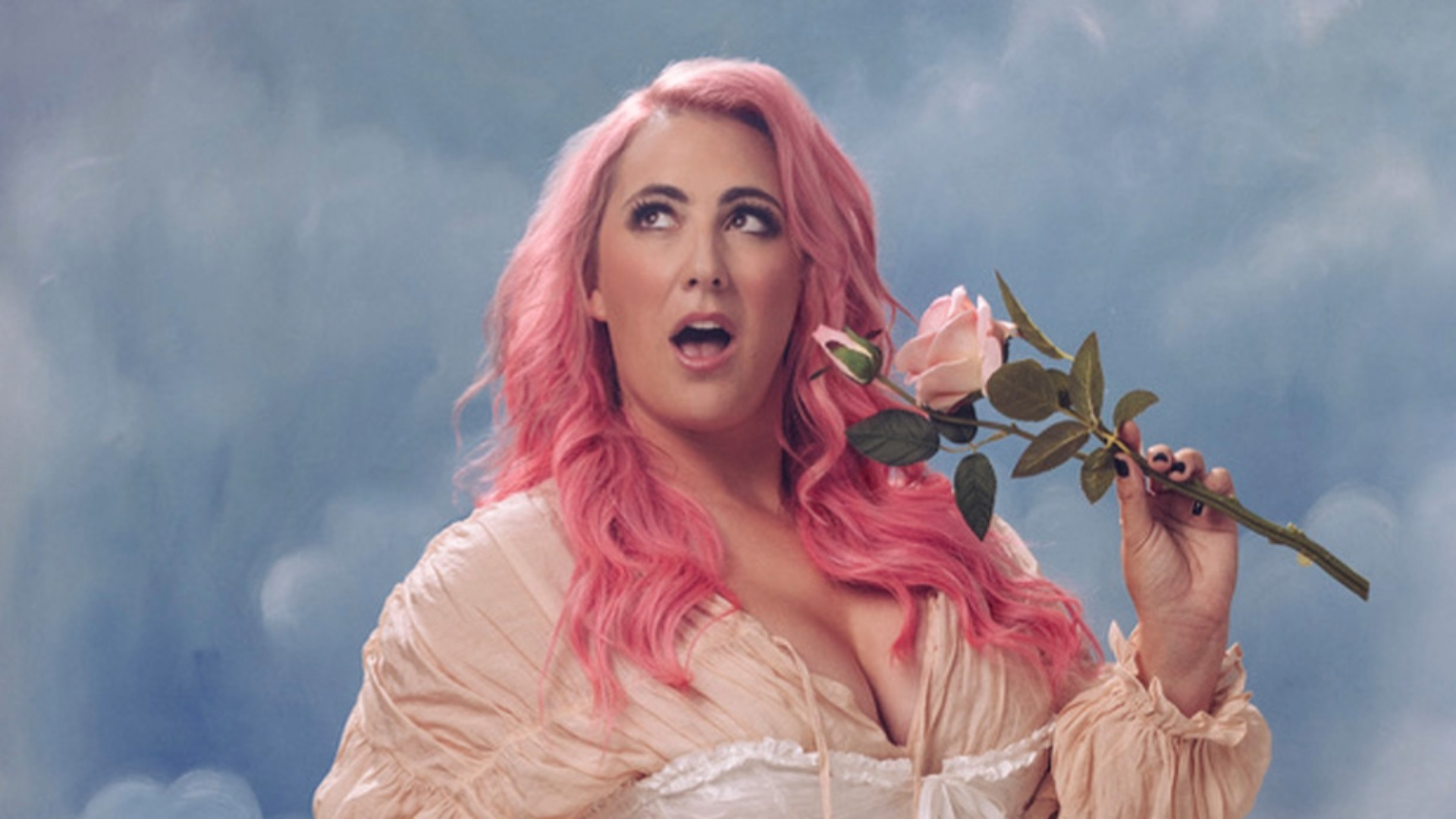 A person with long pink hair and an expressive look holds a pink rose against a cloudy sky backdrop, reminiscent of a theatrical scene. Their light, flowing outfit flutters as if captured mid-performance, mouth slightly open in surprise.