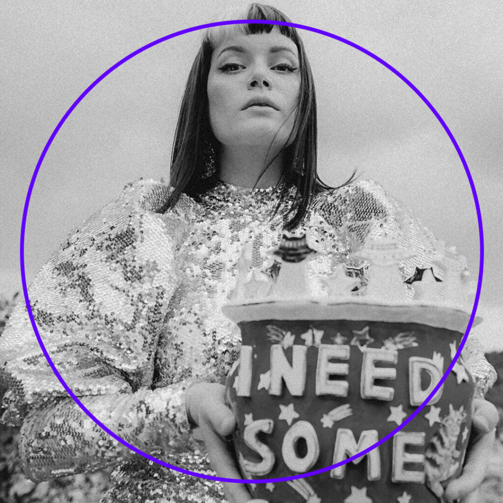 Black and white photo of a person in a sparkling sequin dress, holding a decorative container with I NEED SOME SPACE on it, framed by a purple circle at the Silent Disco Brisbane Powerhouse. The backdrop is an idyllic outdoor setting.