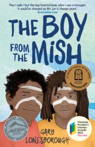 Book cover of The Boy from The Mish by Gary Lonesborough, featuring two Aboriginal boys with white face paint against a blue background. Award stickers and a positive review quote are displayed on the cover.