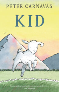 A playful white goat stands on grass in front of a mountain and pastel sky on the cover of Kid by Peter Carnavas. A review quote from The Telegraph appears at the bottom.