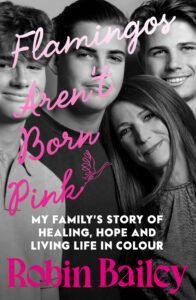 A black-and-white photo of Robin Bailey and her two sons, overlaid with the pink and white text: Flamingos Arent Born Pink. My familys story of healing, hope and living life in colour. Robin Bailey.