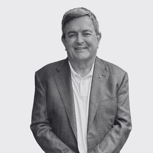 A smiling man wearing a blazer over a polo shirt.
